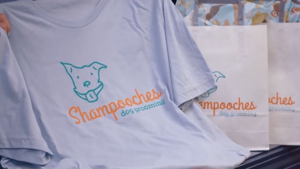 Majica sa logotipom brenda i promo kese na stolu kao primer brendirane opreme