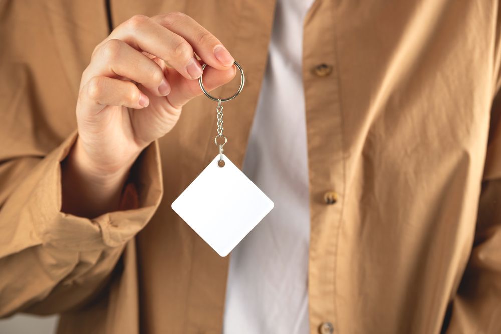 Osoba drži beli reklamni privezak namenjen za brendiranje i promotivne kampanje